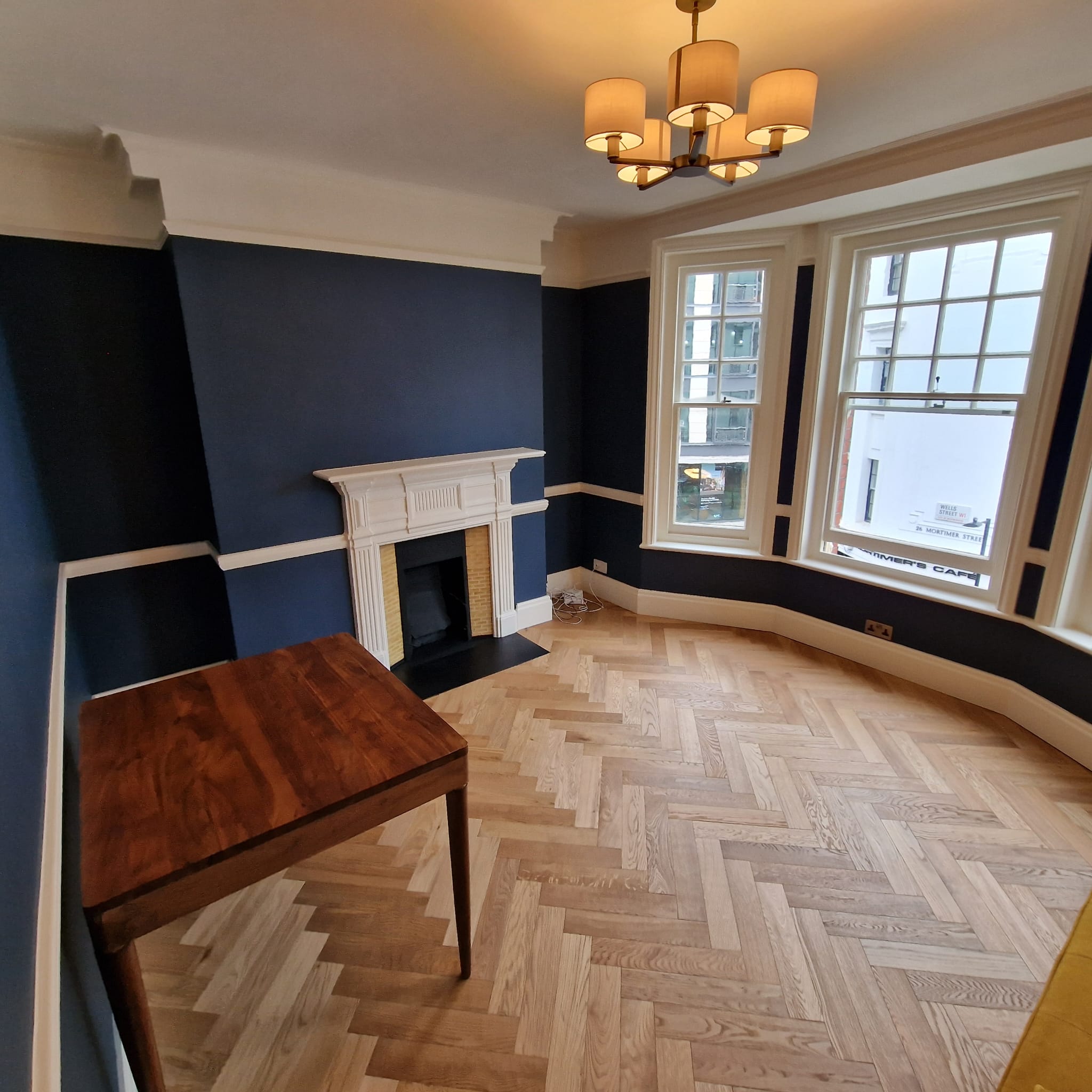 Period room with fireplace, navy walls and herringbone parquet floor