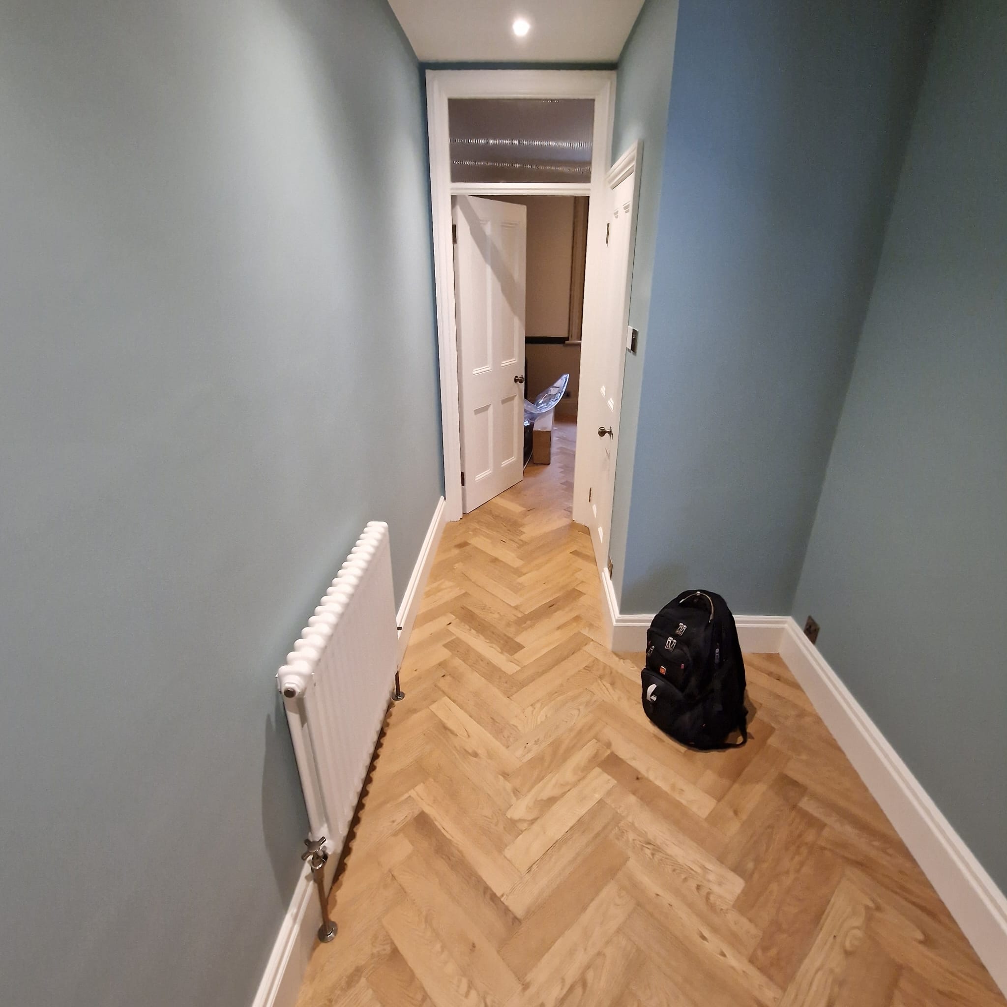 Hallway with fresh herringbone parquet flooring and slate-blue walls