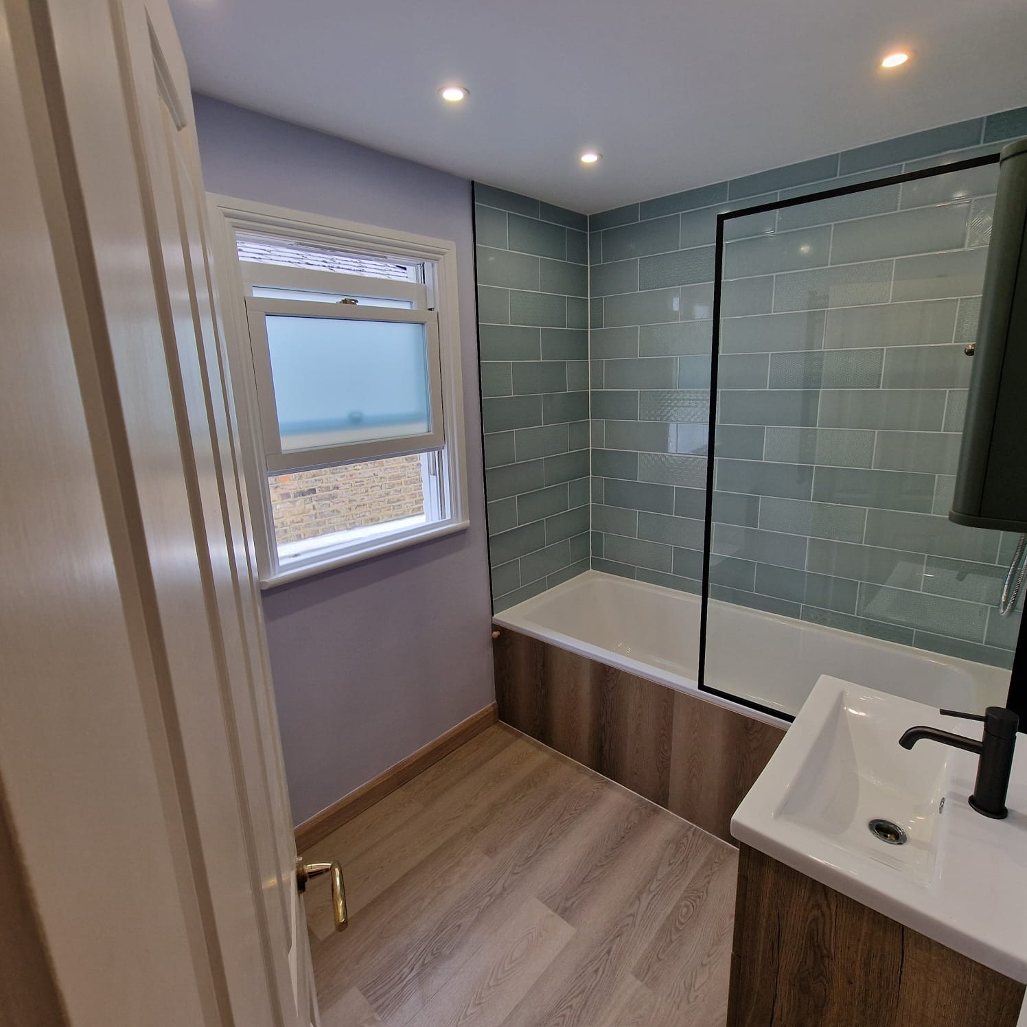 Completed sage-tile bathroom with engineered wood floor