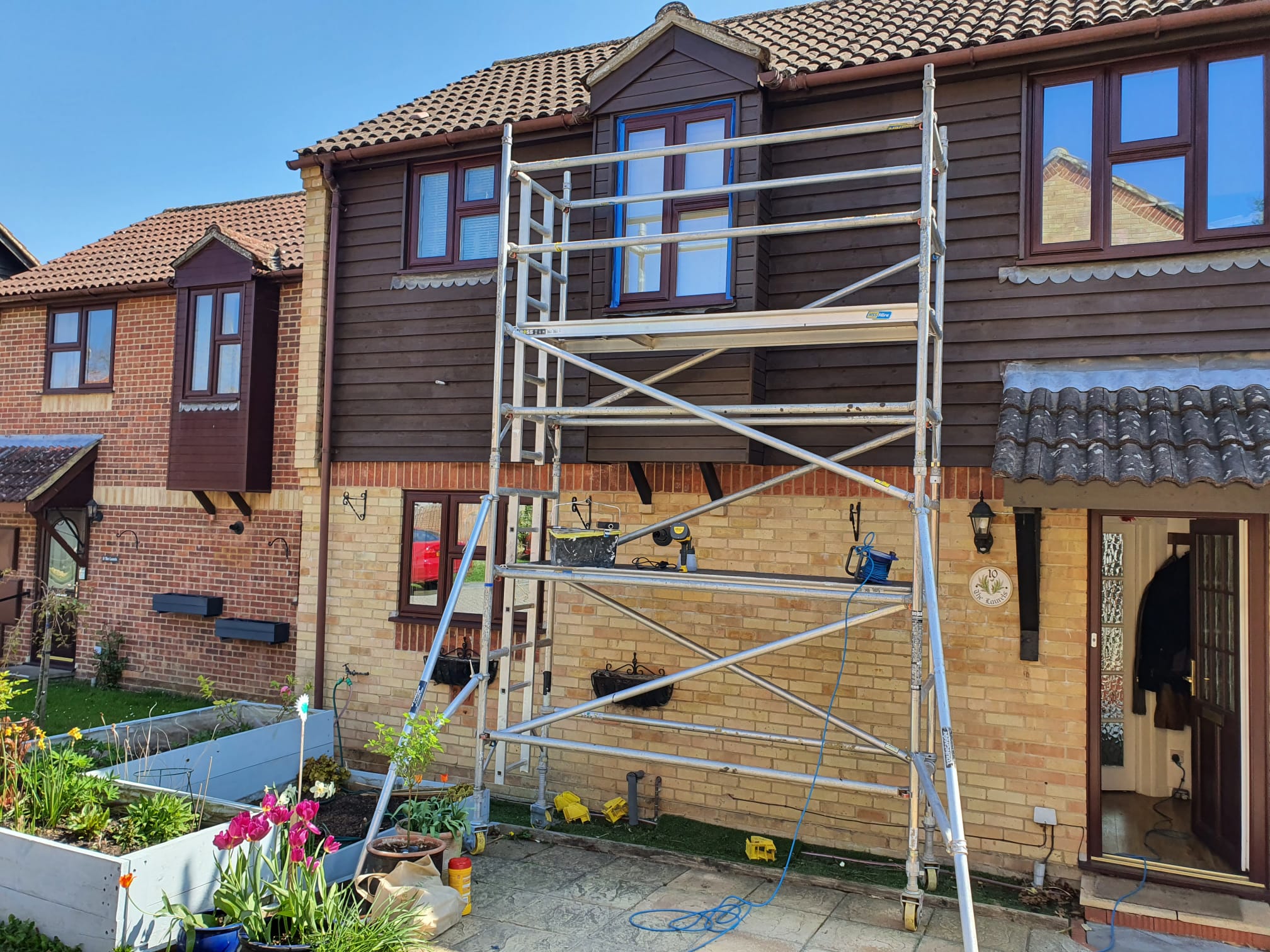 Exterior of a clad house under scaffold tower for full repaint